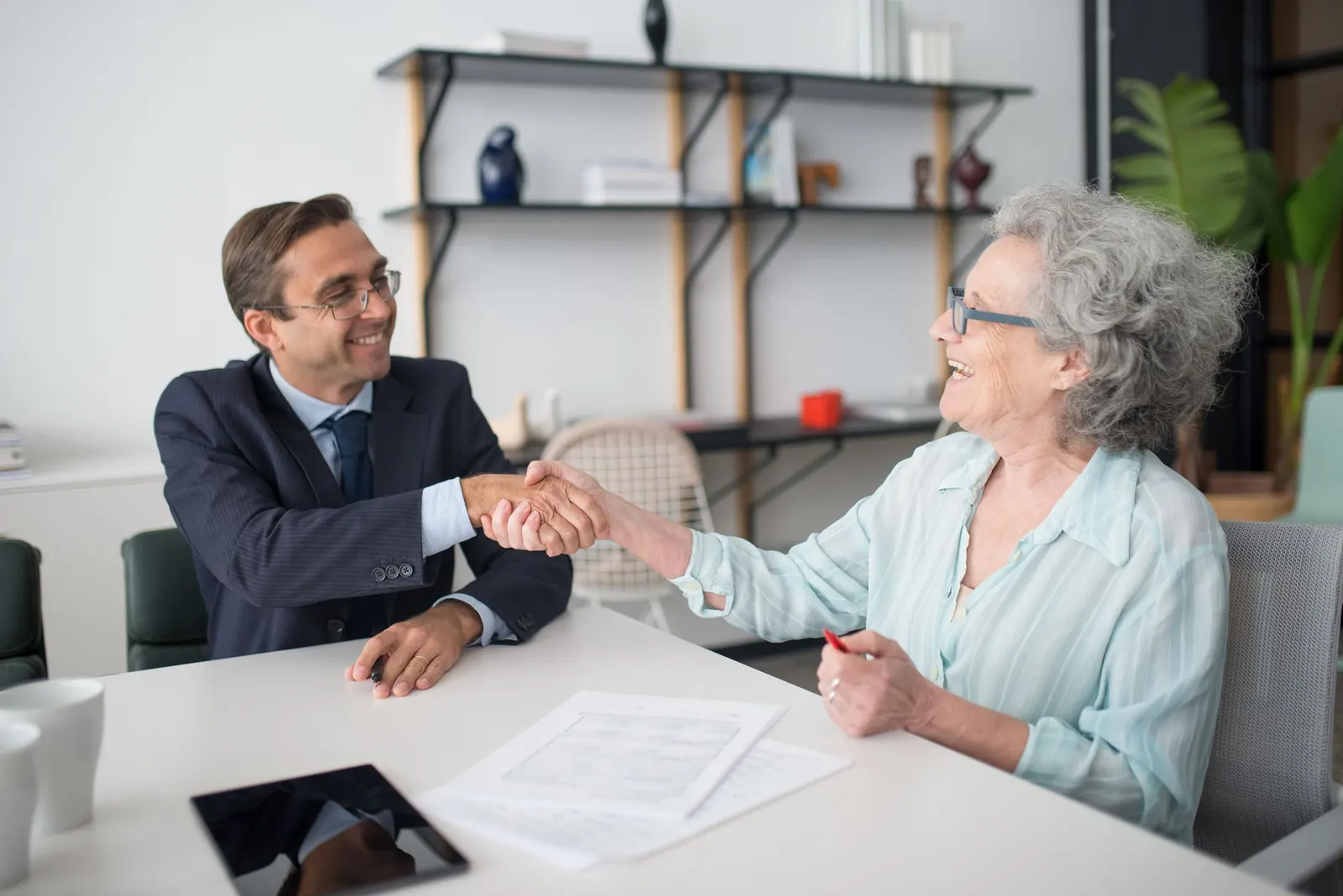 An advisor shaking hands with a client across a desk