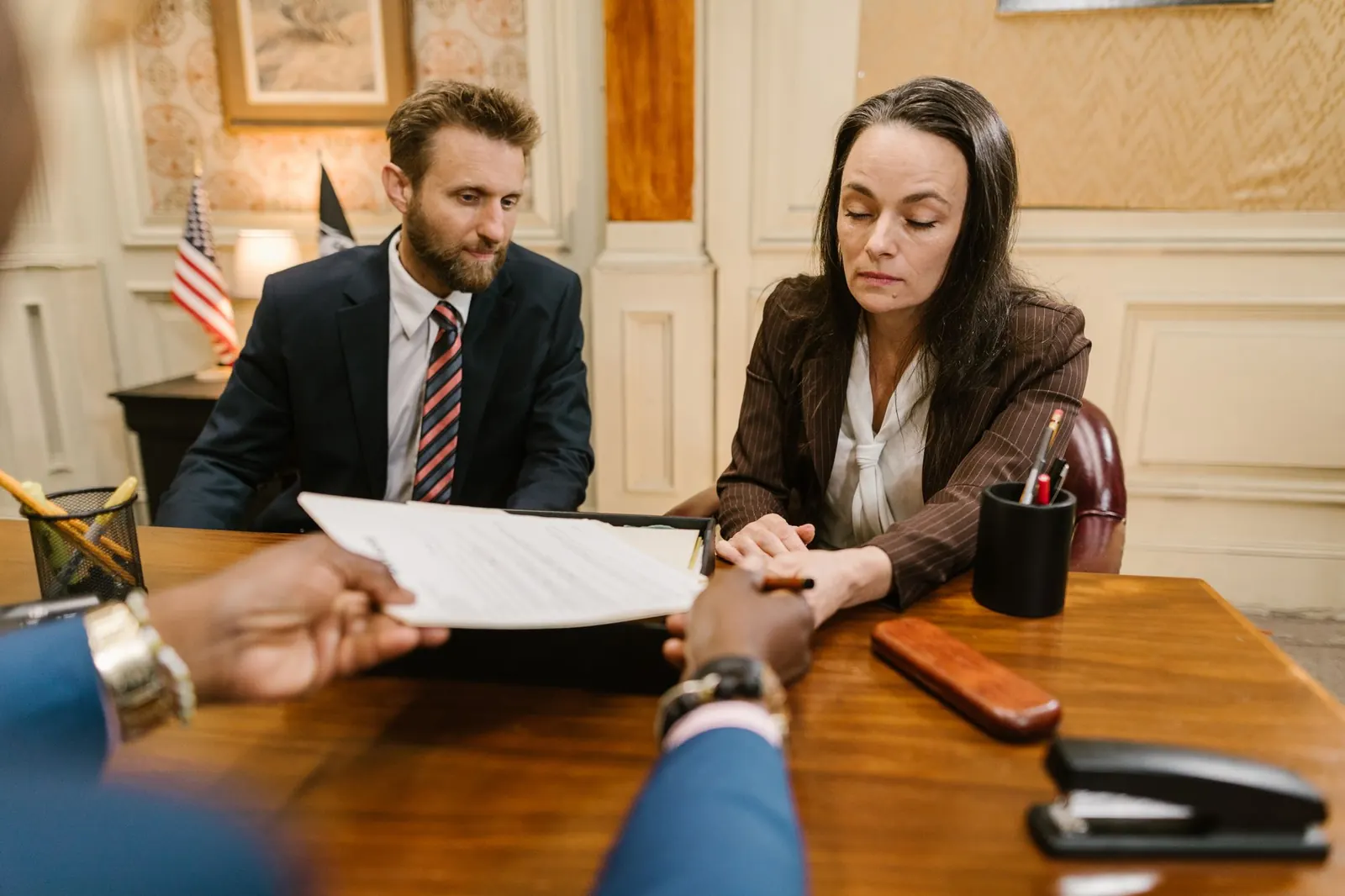 Two colleagues exchanging documents across a desk